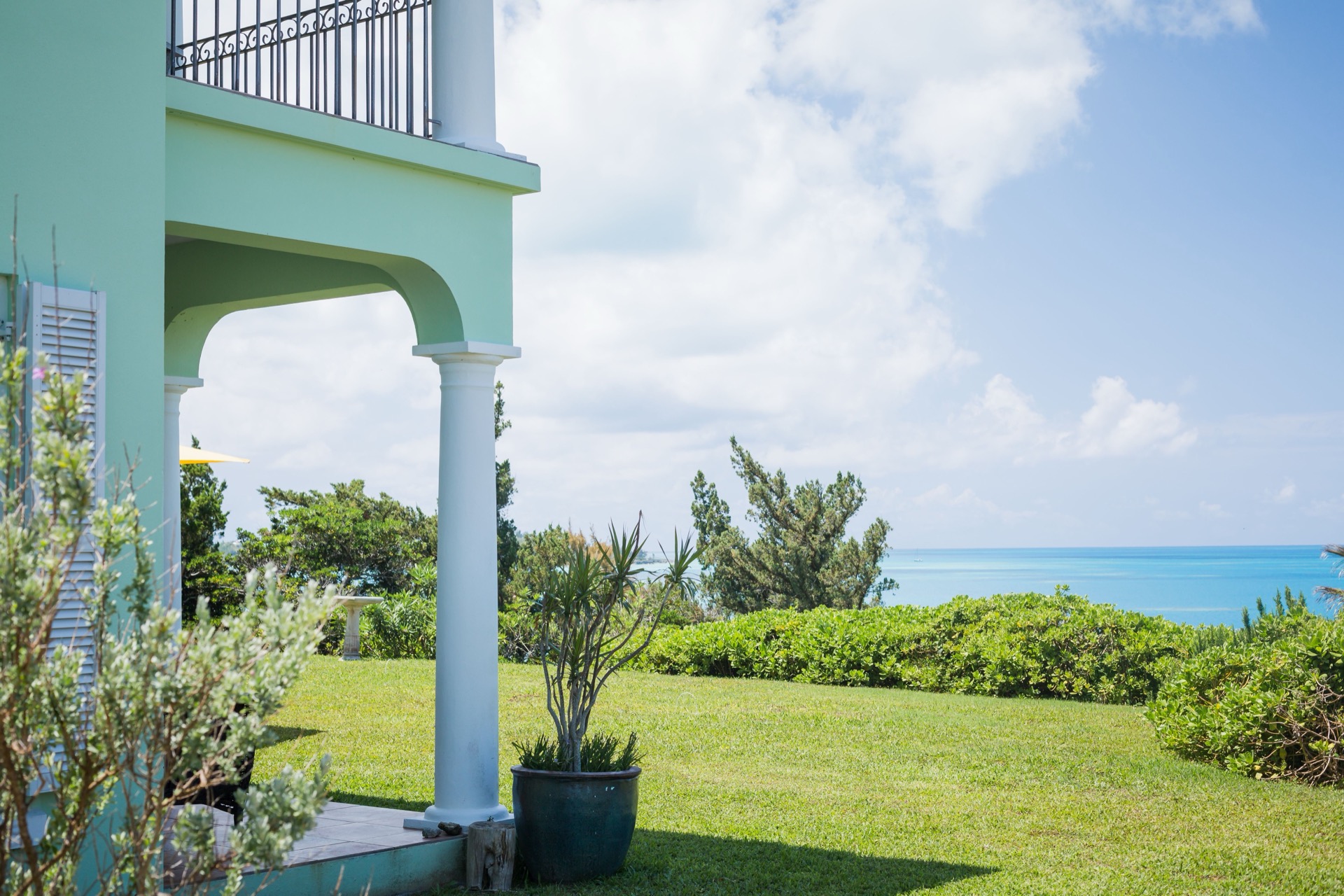 A coastal home with a covered porch looking out over the ocean on a bright summer day